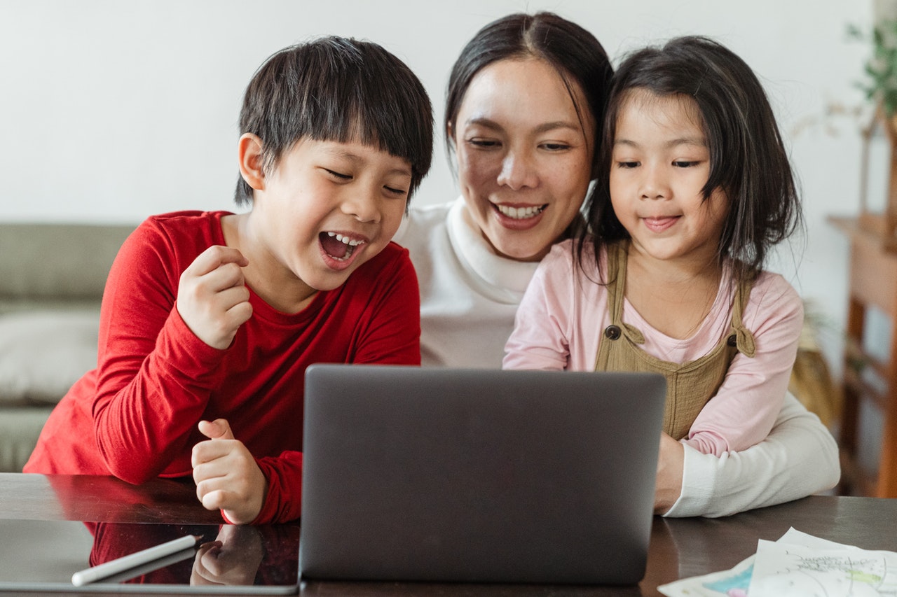 Mother and two children smiling while looking at laptop